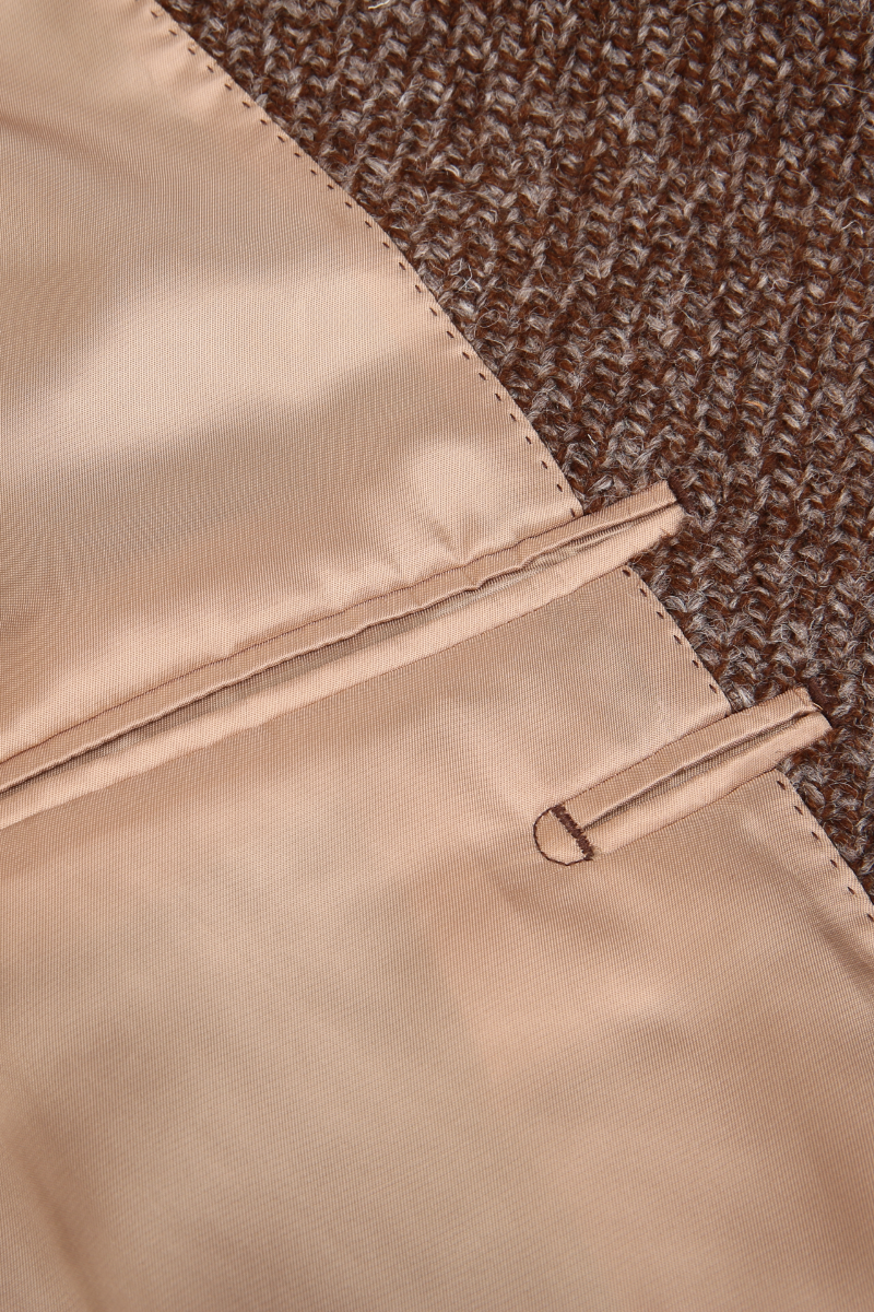 Close-up of beige fabric with a zipper on a textured brown background tweed custom jackets