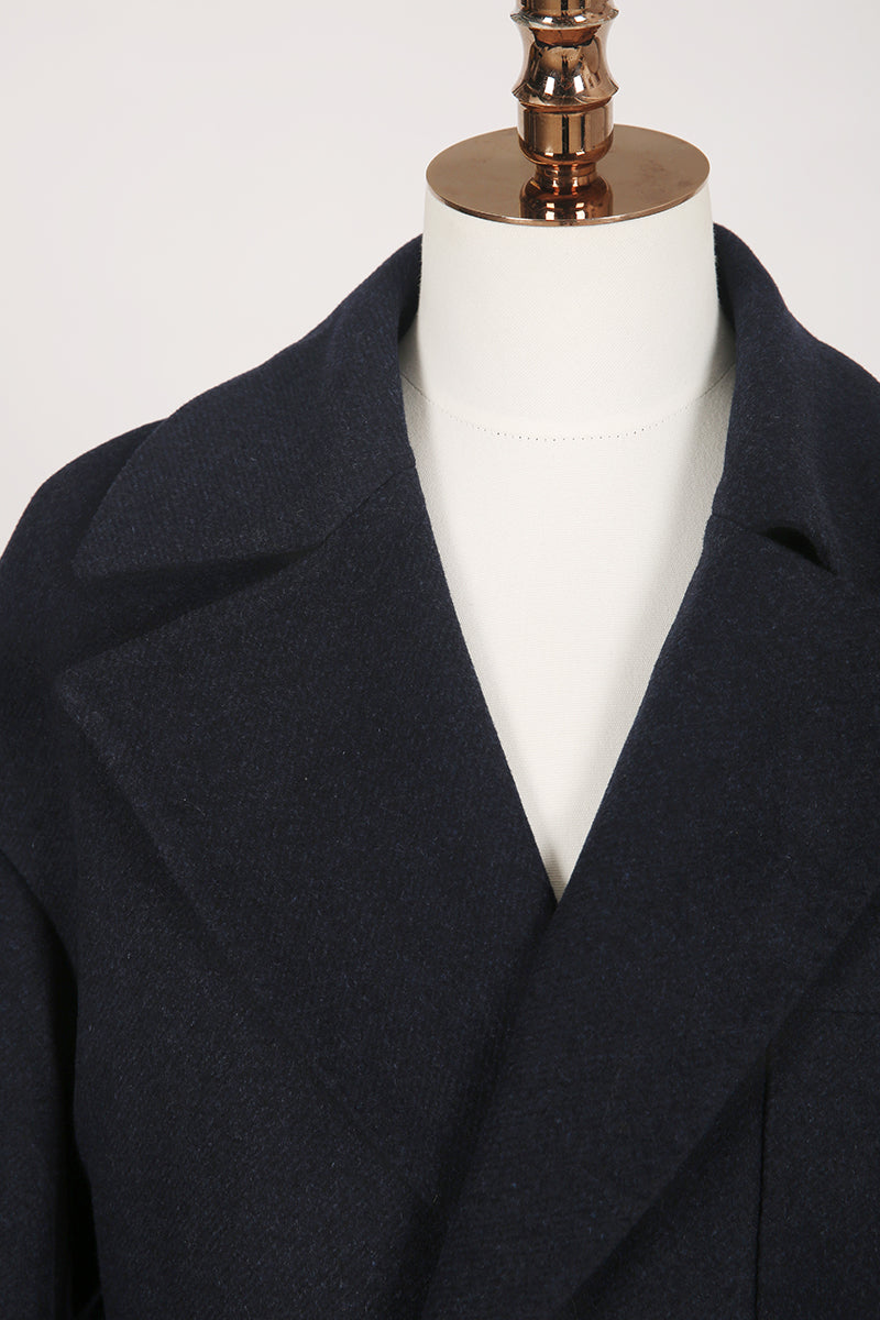 Navy blue coat on a mannequin against a white background