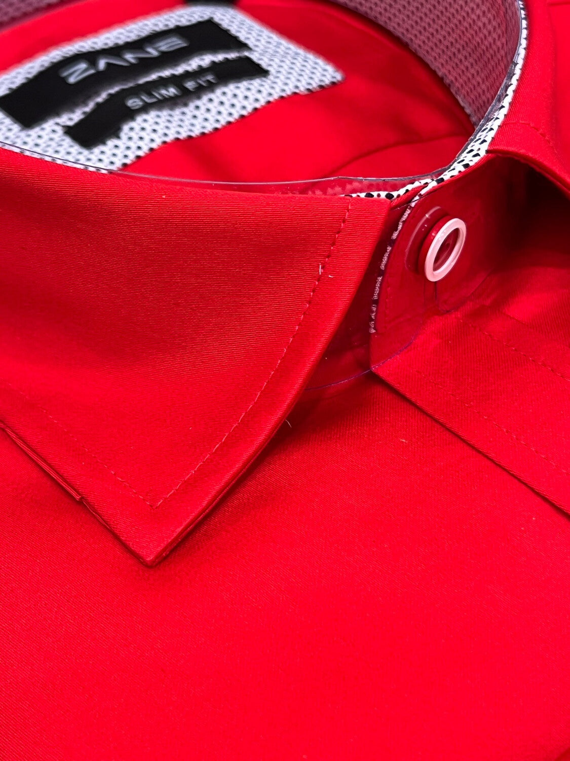 A red slim fit shirt with long sleeves, showing the collar and part of the front panel with a visible logo. Red slim fit mens dress shirt long sleeve cotton formal shirt Jacksonville formalwear Zane Suits and Tuxedos