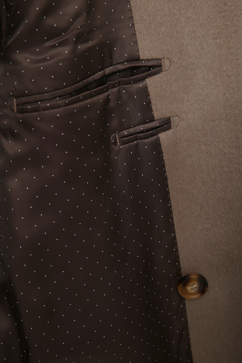 Close-up of a dark brown fabric with white polka dots and a button on a gray background